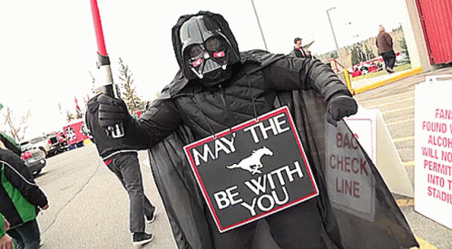 person dressed as darth vader in costume with protest sign