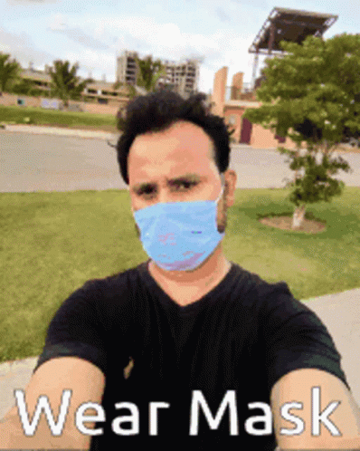 a man wearing a face mask standing by a street