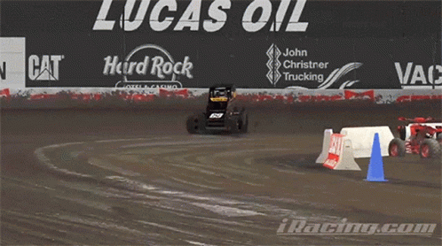 cars racing around a course on dirt with signs behind them