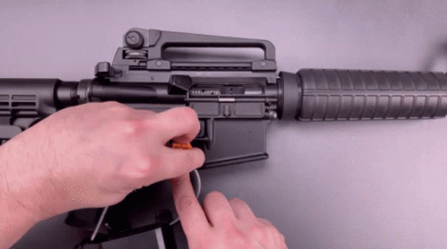 hand pulling a rifle handle with a magnifying tool