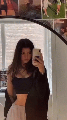 a woman is standing in front of a mirror taking a selfie