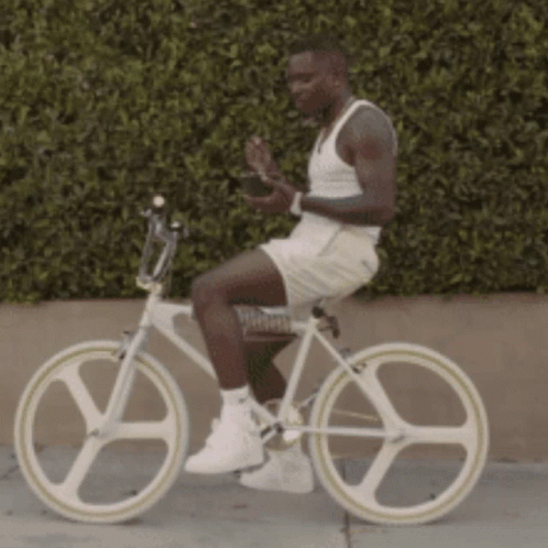 a male athlete in all white is on his bike