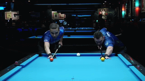 a pair of men playing pool in a bar