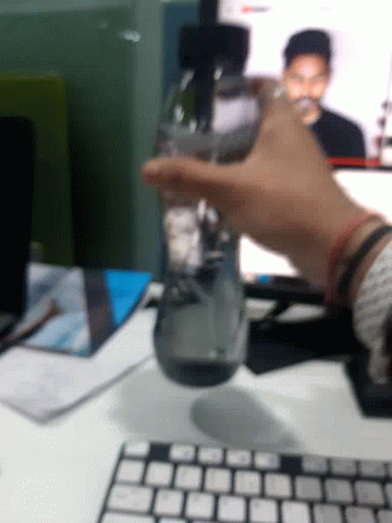 an blurry hand on a keyboard and a bottle