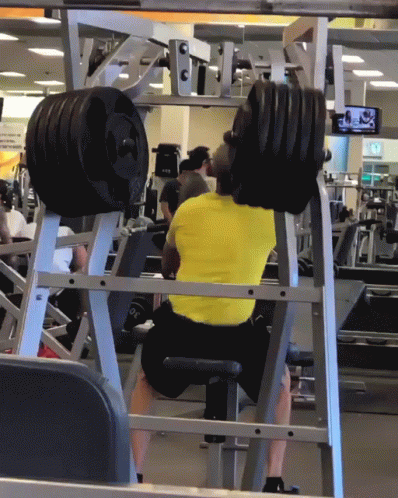 a man squats in the middle of a gym