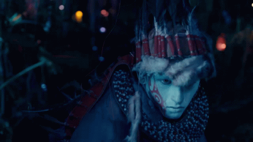 a mask with feathers is shown in a dark scene
