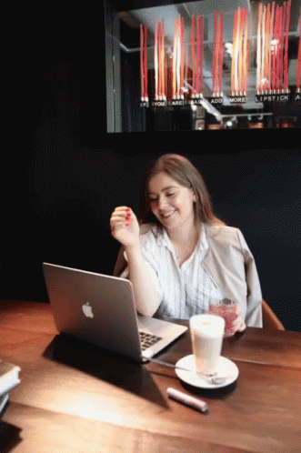 a woman at a table with a laptop and drinks