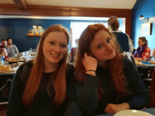 two pretty young ladies sitting at a dinner table