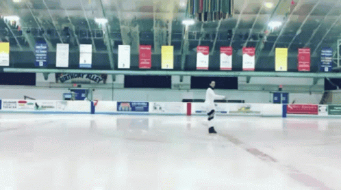 two people skating around an indoor rink, all on ice