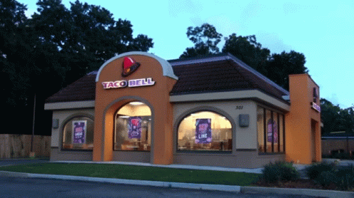 a small taco bell sitting outside of a fast food restaurant