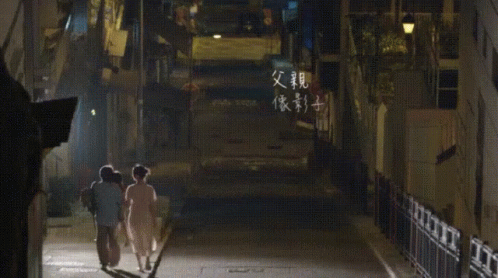 two people are walking down a dark street