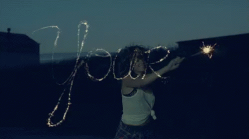 woman with long hair holding sparklers and looking at camera