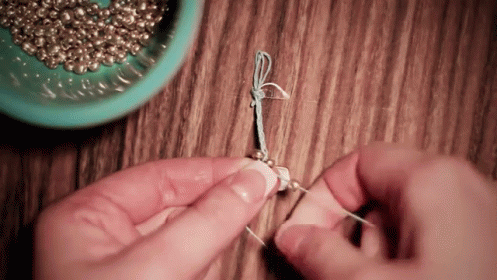 a person is knitting thread in front of some beads