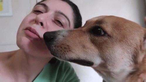 a woman who is brushing her teeth while next to a dog