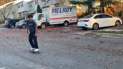 a man riding on top of a skateboard next to cars