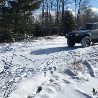 a gray suv driving down a snowy road in the woods