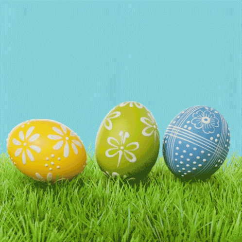 three painted eggs sitting in the grass