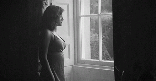 a woman in short clothing standing next to a window