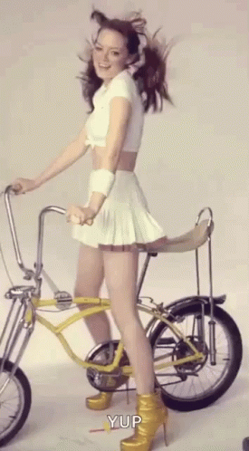 there is a woman standing on a bike wearing blue high heels