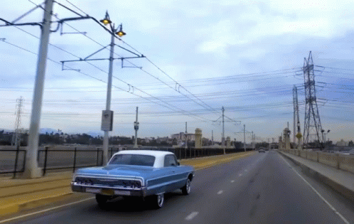 a brown car driving down a bridge near power lines