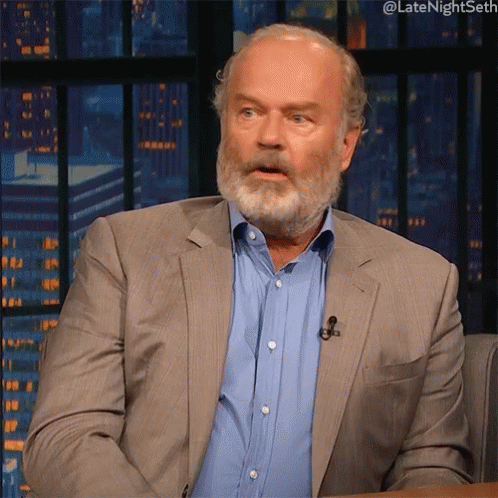 a bearded man is talking on a tv set