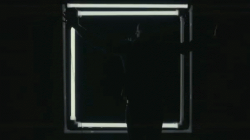 a person in the dark with arms outstretched towards a doorway