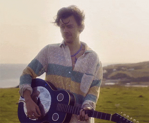 a man holding a guitar and wearing a striped shirt