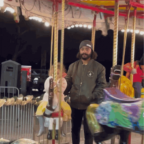 a man standing on a merry go round with a beard and long black hair