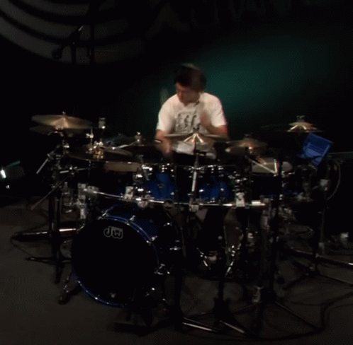 a person standing in front of a black drum kit