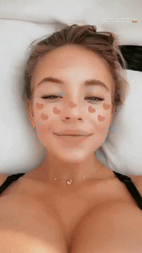 a woman laying in bed with her face painted in light blue