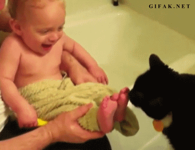 a baby holding an arm on the ground in front of a cat