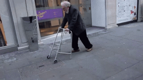 an old person walking down a sidewalk with an walker