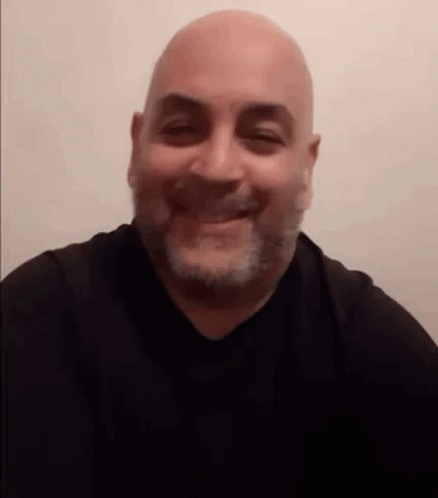 a bald man in a black shirt smiles