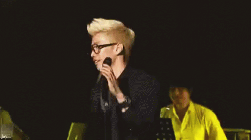 the male musician is singing into his microphone while on stage