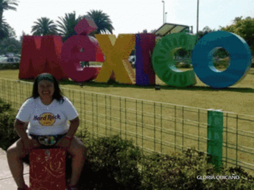 a woman sits on a skateboard next to the sign of mexico