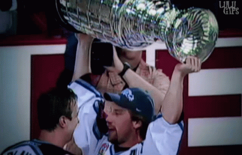 some men with a trophy and one person holding a bottle