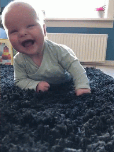 baby crawling on the floor while playing with the carpet