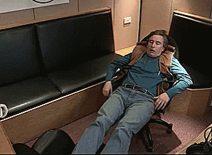 a man sitting on an airport chair has his head down