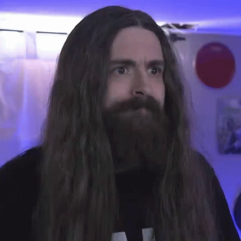 a man with long hair is looking in the camera