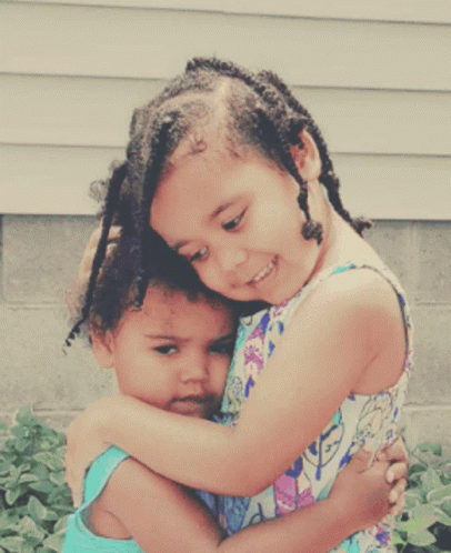 two small children hug each other outside