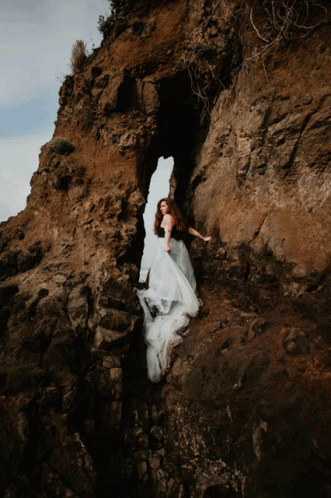 a woman is climbing up a mountain next to the ocean