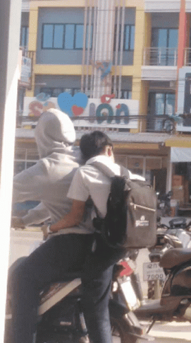 two people riding on the back of a motorcycle