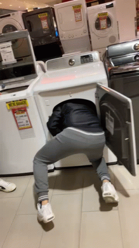 a man sitting next to the washers with his head in his machine
