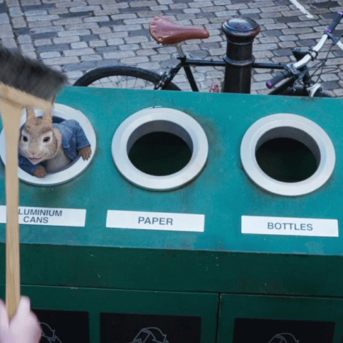 a hand holds the tail of a green cart near two toilet paper dispensers and an odd image of a bunny on top of another green cart