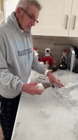 an older man cleaning the kitchen counter with gloves