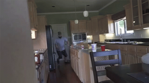 an older man walking down the kitchen with a chair