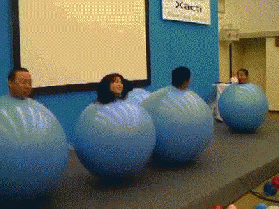 a group of people sitting on plastic balls in front of a projector screen