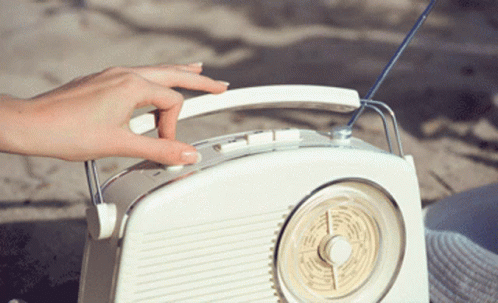 a person's hand and a radio on a table