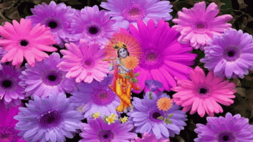 a small figurine is among pink flowers