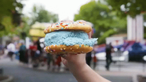 a person holding up a doughnut that has frosting on it